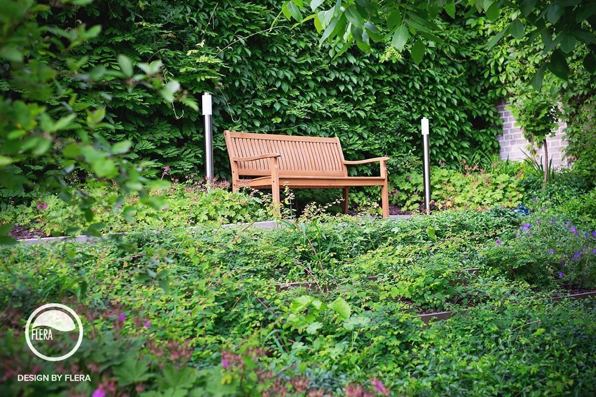 Krásna záhrada s drevenou lavičkou a bohatou zeleňou